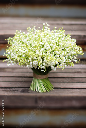 white lush bouquet of lilies of the valley on wooden steps