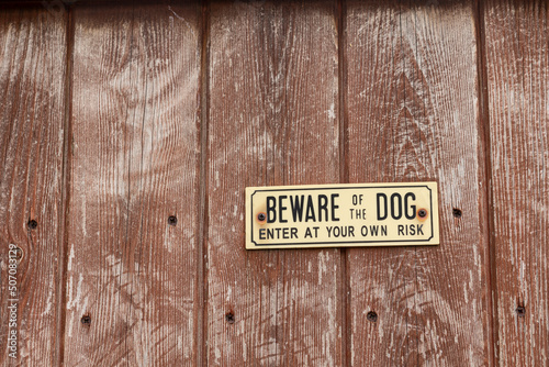 beware of the dog sign on a wooden panel fence photo