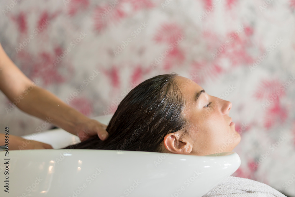Side view of Hairdresser hands washing hair of a beautiful young woman in hair salon. Side view of Hairdresser hands washing hair of a beautiful young woman in hair salon.