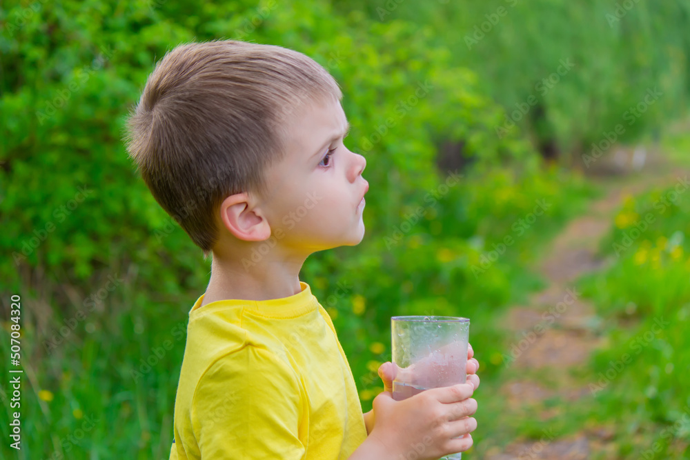 The boy drinks water from a glass. Pure water. Summer. The boy drinks water from a glass. Pure water. Summer.
