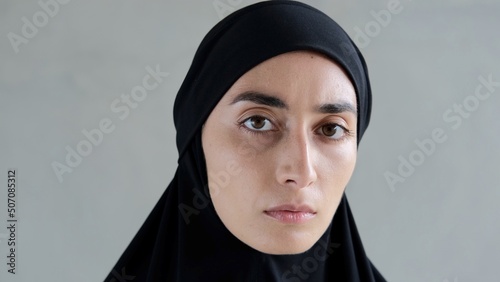 A sad woman in a black hijab looks up filled with pain and despair and stares intently into the camera. Cruel Islamic world with strict rules of the Muslim religion that restrict the rights of women.