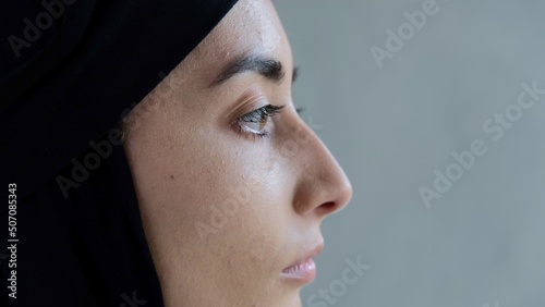 Close-up profile of the face of an Arab woman in a black hijab. An Islamic world that professes Islam and forces women to cover their hair with a scarf from other peoples views in their direction. photo