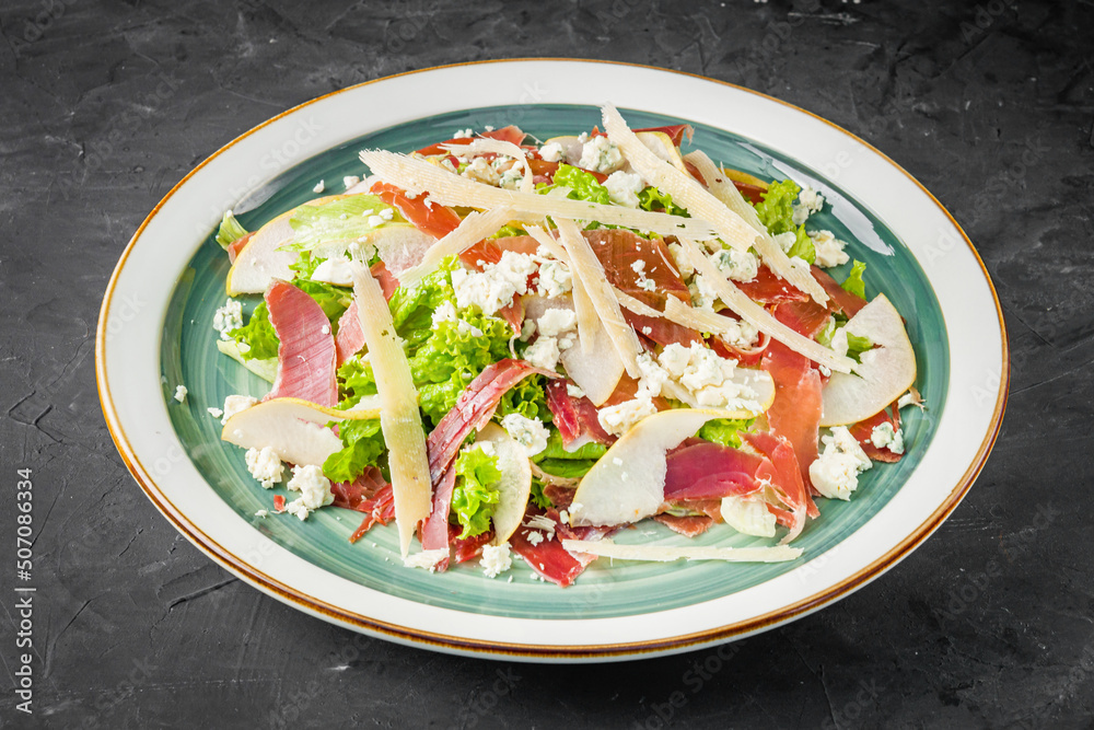 prosciutto salad with parmesan pear and blue cheese on a black background prosciutto salad with parmesan pear and blue cheese on a black background