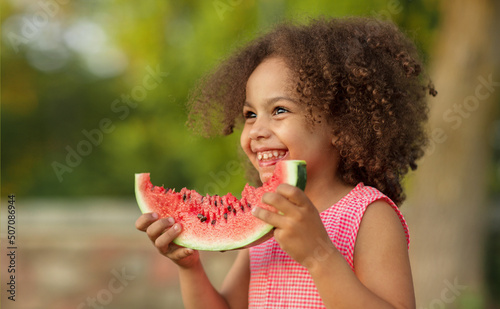 Funny Black kid eating watermelon outdoors in hot summer. Laughing baby, healthy food photo