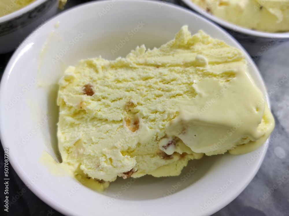 Picture of ice-cream being cut in slices with a knife for serving shot in a kitchen in indoors during summers Picture of ice-cream being cut in slices with a knife for serving shot in a kitchen in indoors during summers