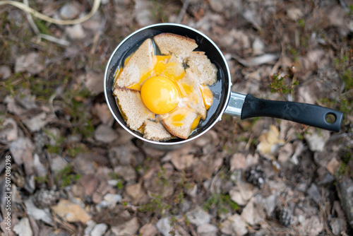 breakfast of eggs and bread in the wild forest by the lake on a fire