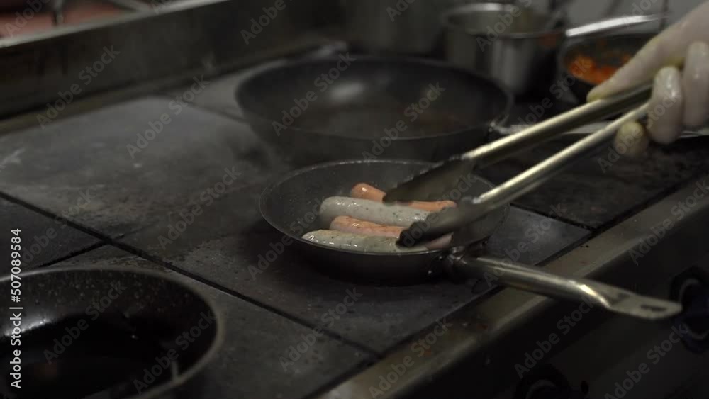 chef frying sausages in a frying pan chef frying sausages in a frying pan