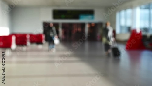 people pulling trolley bags arriving and departing terminal travelling and walking in lobby