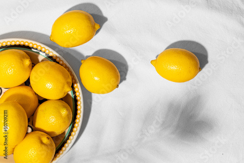 Plate with fresh lemons in a ceramic plate on the table covered with a linen tablecloth. Copy space