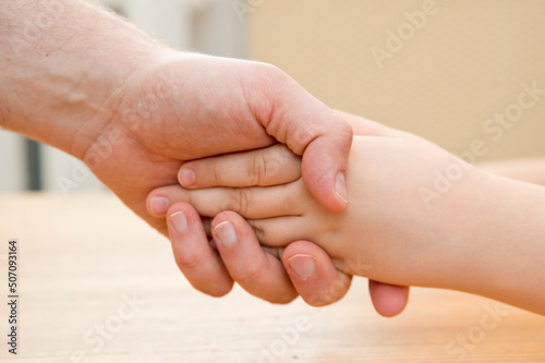 Kids hands in the fathers palms. Parenting, friendship, guardianship, upbringing, parent-child relationship, family connection. © Birute