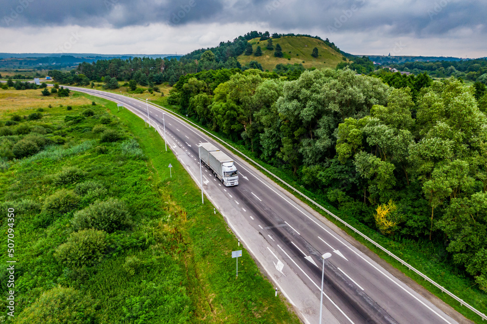 white truck driving on asphalt road on the highway. seen from the air. Aerial view landscape. drone photography. cargo delivery white truck driving on asphalt road on the highway. seen from the air. Aerial view landscape. drone photography. cargo delivery