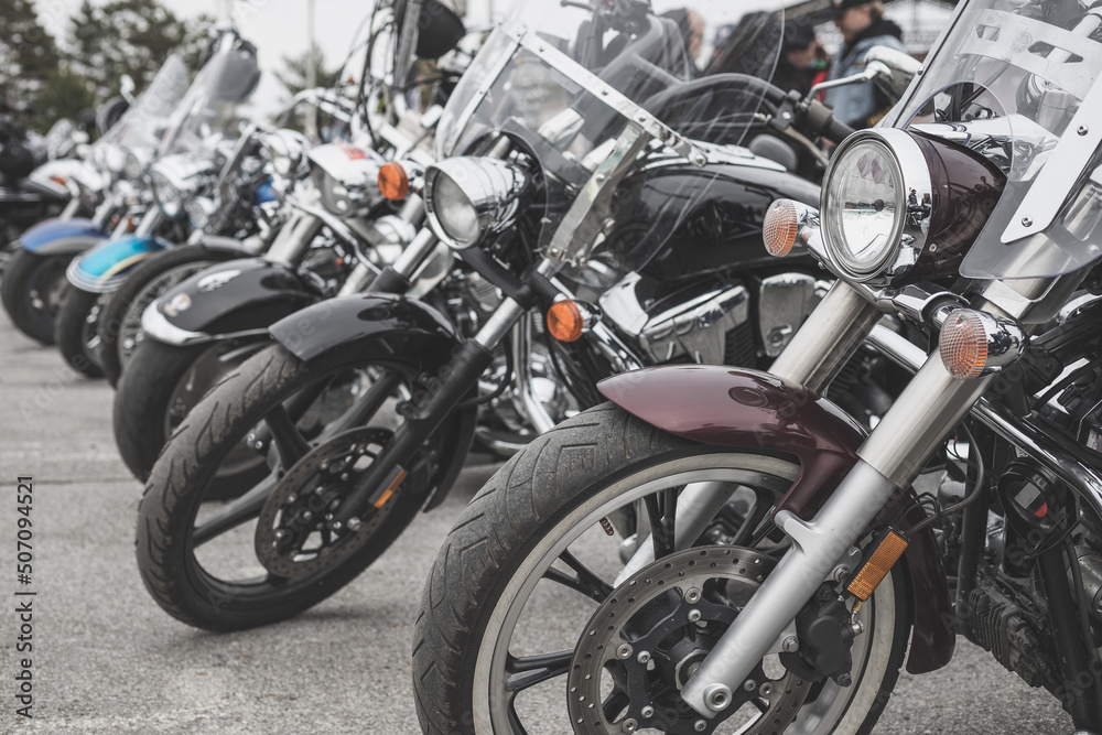 Motorcycles parked in a line in a motorcycle parking lot. Close-up of the front wheel of a motorcycle