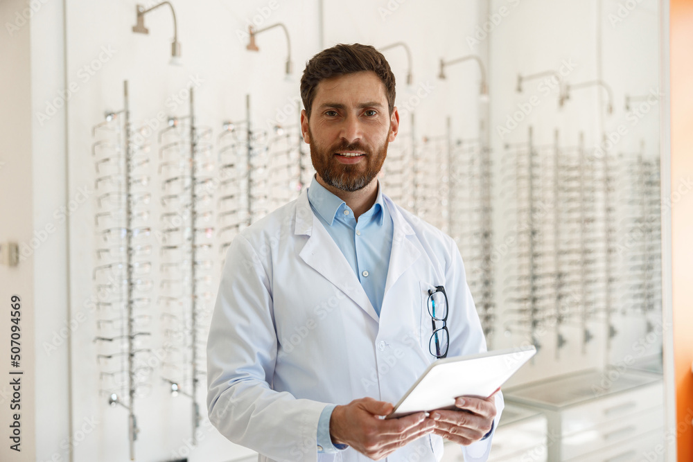 ophthalmologist with eyeglasses using digital tablet while working in optics store