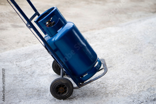 Фотография Blue LPG gas cylinder tank on small cart to make delivery to local customers in rural of Thailand