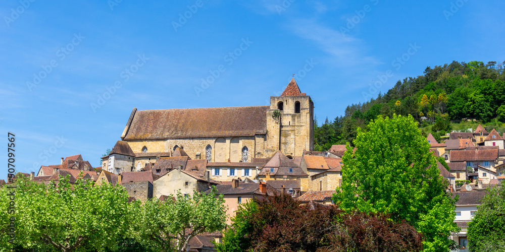 view of the historic village center of Saint-Cyprien with traditional brown stone houses and catholic church
