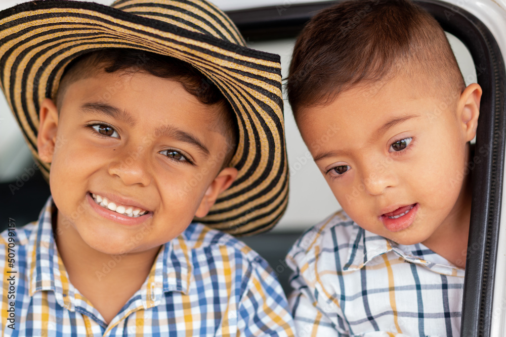 Portrait of two children. Happy and tender Colombian brothers smiling and looking at the camera. Down's Syndrome Portrait of two children. Happy and tender Colombian brothers smiling and looking at the camera. Down's Syndrome