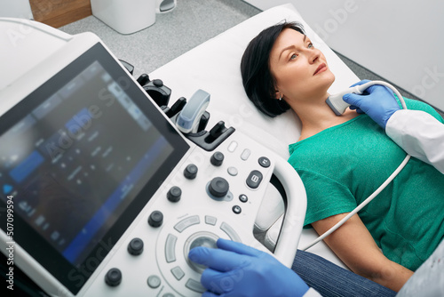 Ultrasound diagnostics of endocrine system and thyroid for woman. Female patient receives thyroid diagnostics. Treatment of thyrotoxicosis and hypothyroidism photo