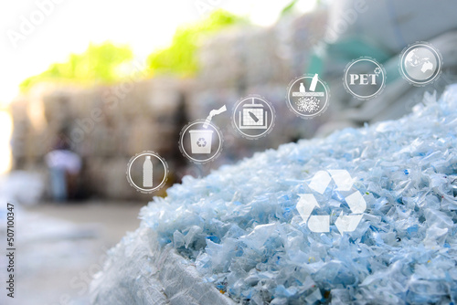 Close up PET plastic bottle flakes in white big bag with blur plastic bottle bales background, recycle icon, sustainable icon and Bottle icon. Chemical concept
