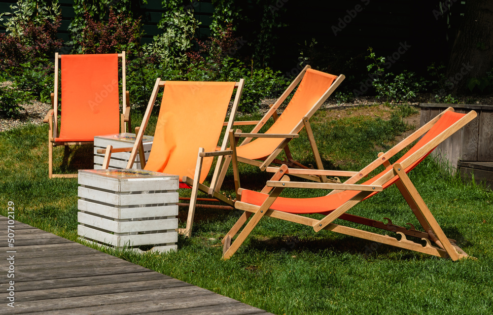 Orange lounge chairs in a green summer garden Orange lounge chairs in a green summer garden