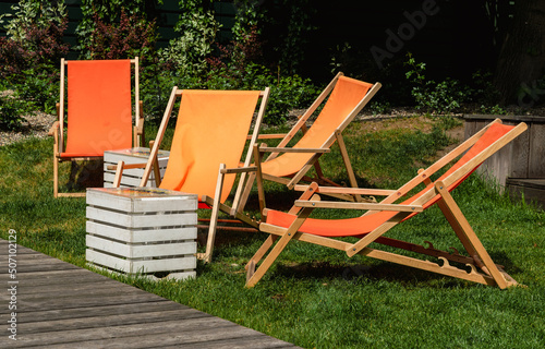 Orange lounge chairs in a green summer garden