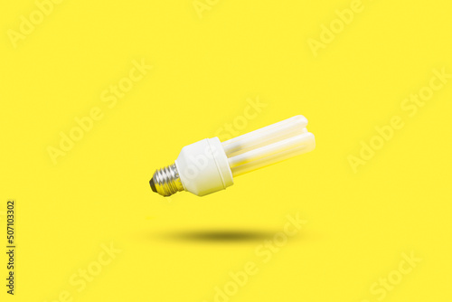 Bombilla de luz bajo consumo sobre un fondo amarillo brillante liso y aislado. Vista de frente y de cerca. Copy space photo