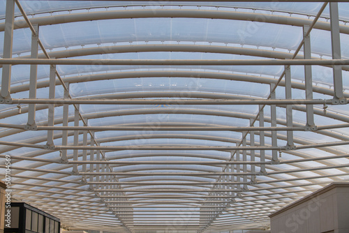 Modern futuristic ceiling of shopping mall. Transparent abstract glass roof structure inside shopping center.