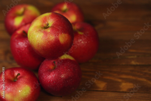 Heap of red wet apples on wooden table.