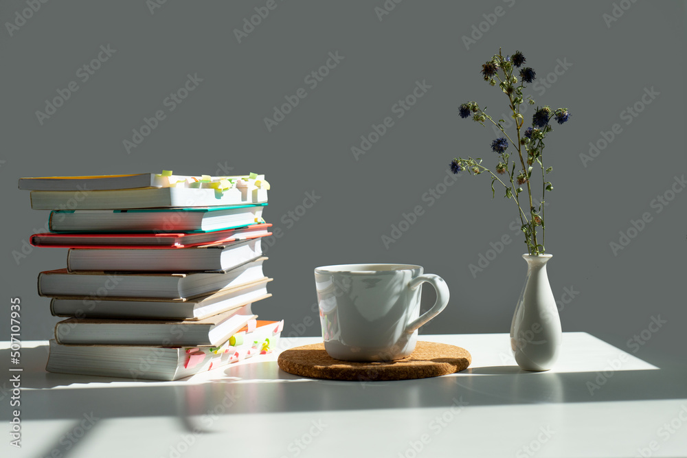 books, a mug of tea and a vase of flowers. books, a mug of tea and a vase of flowers.