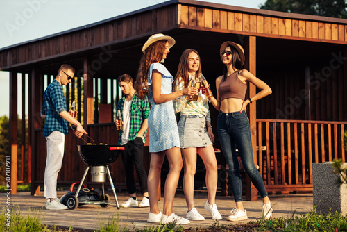 Canvas Print Three girls are drinking drinks , in the background a group of friends having fu