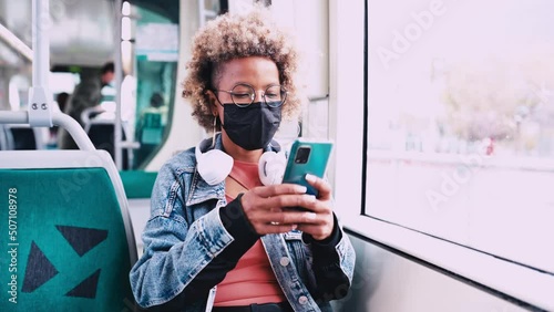 A young lady wearing facial mask using a smartphone in the train. Medium shot.