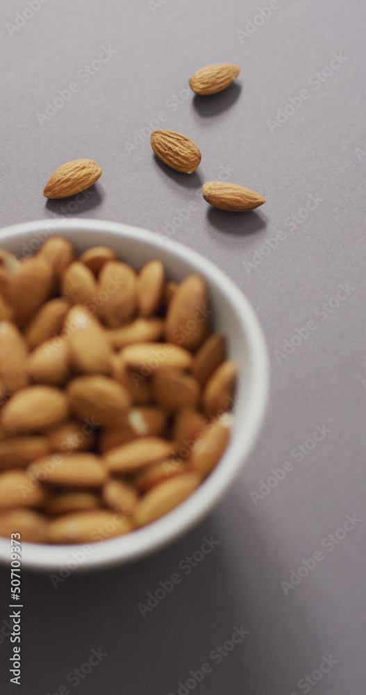 Vertical image of a bowl of almonds on a lilac background Vertical image of a bowl of almonds on a lilac background