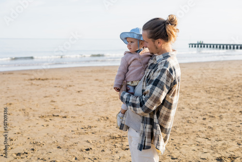 Parent looking at daughter in panama hat on beach in Treviso. © LIGHTFIELD STUDIOS