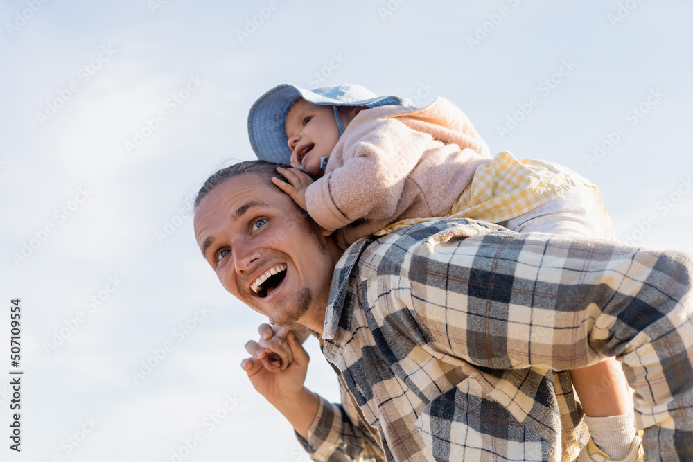 Low angle view of positive father and baby girl having fun with sky at background. Low angle view of positive father and baby girl having fun with sky at background.