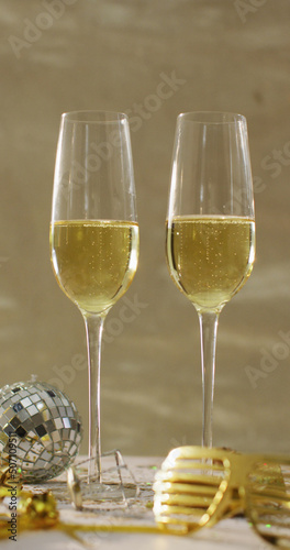 Vertical image of two glasses of champagne, mini disco ball and party glasses