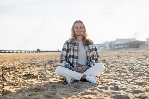Cheerful long haired man looking at camera on beach in Italy. © LIGHTFIELD STUDIOS