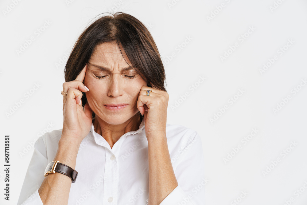 Mature woman with headache frowning while rubbing her temples Mature woman with headache frowning while rubbing her temples