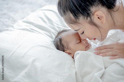 baby sleeps asian mother and touches her child with tenderness and cherishness