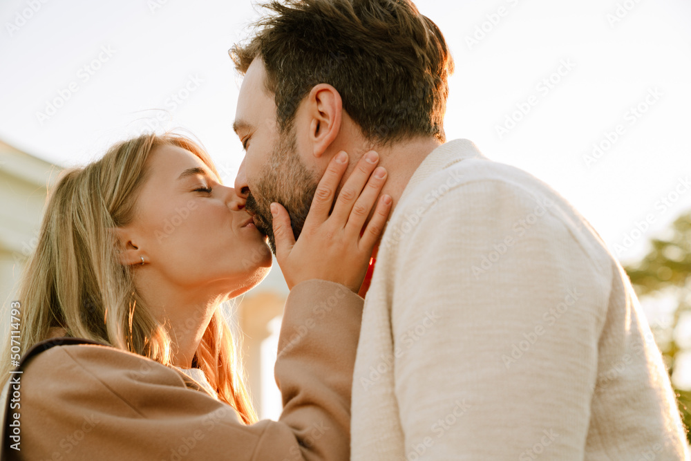 White romantic couple kissing and hugging while walking in park