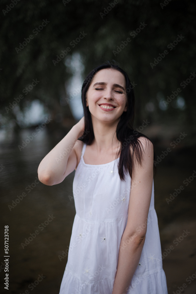 Beautiful sexy girl in a short white dress in nature near the river