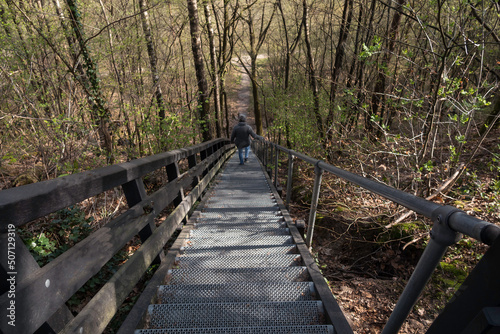adult woman walks down a large metal staircase in the forest