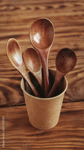Wooden spoons in a paper cup on a wooden table