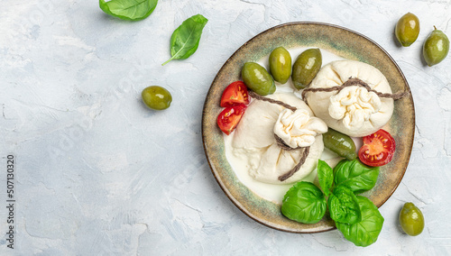 Italian burrata cheese with olives and cherry tomatoes, basil, olive oil on light background. Long banner format. top view