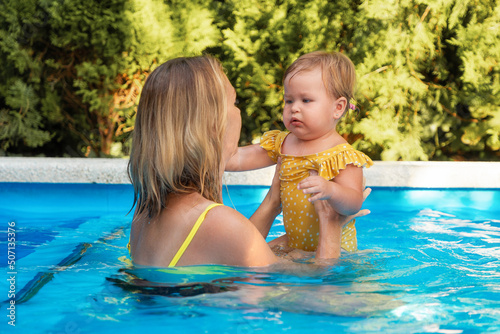Young woman instructor learning little girl to swim in a pool © _KUBE_