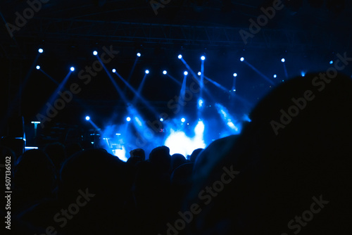 Silhouette of People in the concert area with spotlights on the stage