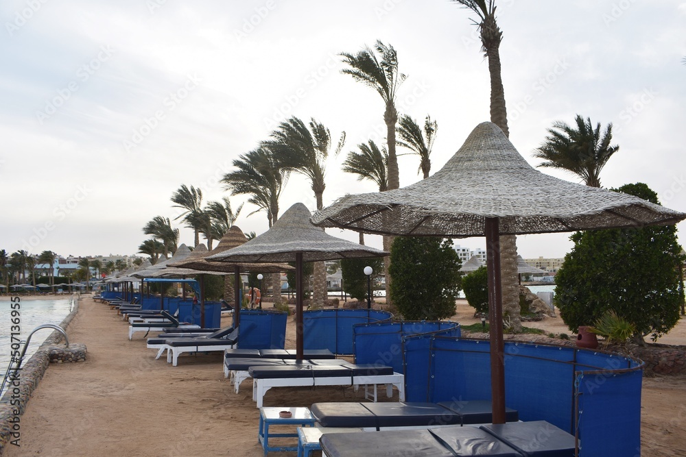 Row of sunbeds and umbrellas, on a beach in Hurghada, Egypt, on a cloudy day.