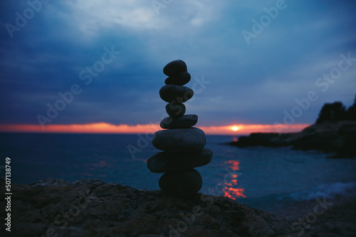 Silhouette of balanced zen stones on the ocean beach ant sunset sunrise time.