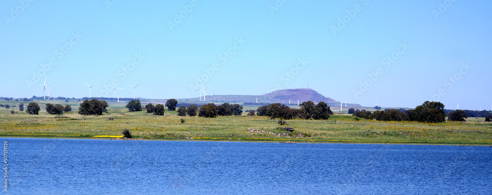 Panoramic view of Lake Shabania in the Golan Heights overlooking a green plain and a mountain range in the distance.