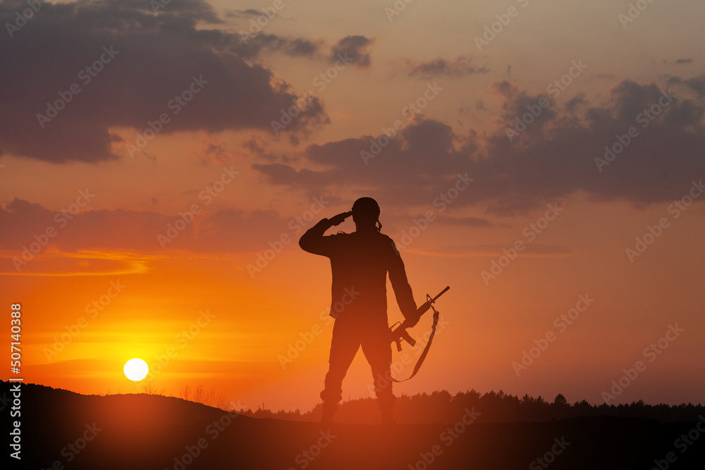 Silhouette of soldier standing against the backdrop of a sunset. Greeting card for Veterans Day, Memorial Day, Independence Day. USA celebration. Concept - patriotism, protection, remember honor. Silhouette of soldier standing against the backdrop of a sunset. Greeting card for Veterans Day, Memorial Day, Independence Day. USA celebration. Concept - patriotism, protection, remember honor.