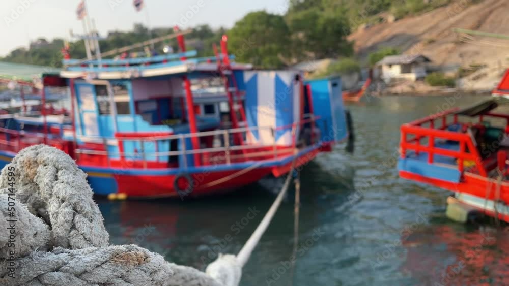 Close up rope tie docking fishing boat floating at pier. Boats floating