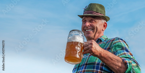 Senior men with beer mugs with Bavarian beer in Tyrolean hats celebrating a beer festival in Germany. Happy old people during the October holiday in Munich photo